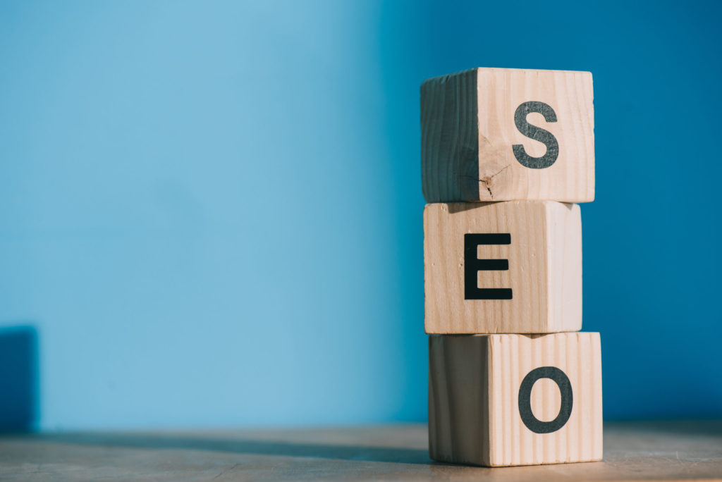 SEO word made from wooden alphabet cubes on blue background