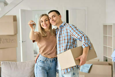 Happy young couple first time home owners holding keys in new home.