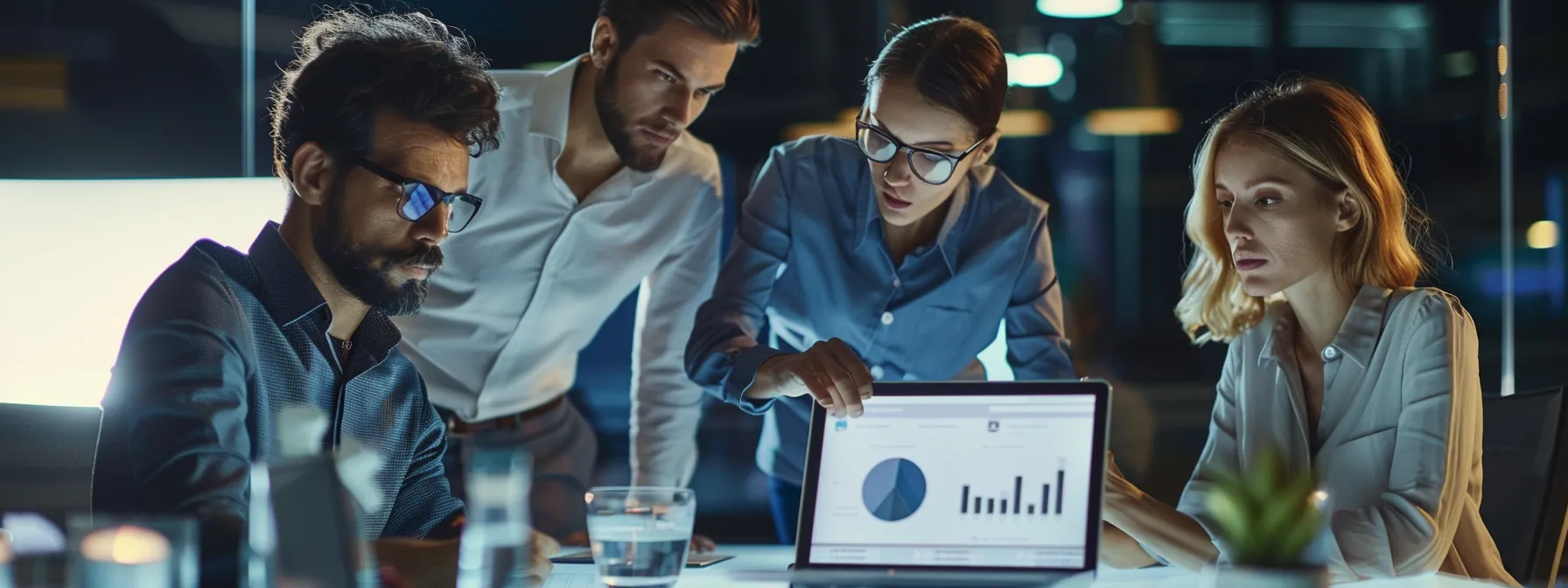 business professionals engaged in a focused discussion around a laptop displaying analytics.